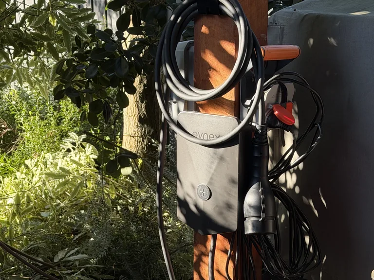 Evnex charger post-mounted outdoors with the charging lead coiled on a hanger