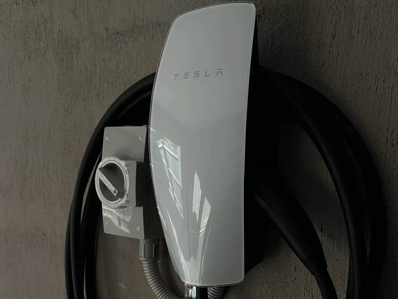 Tesla Wall Connector installed by Mathie Electrical with an isolator and the lead coiled on the wall