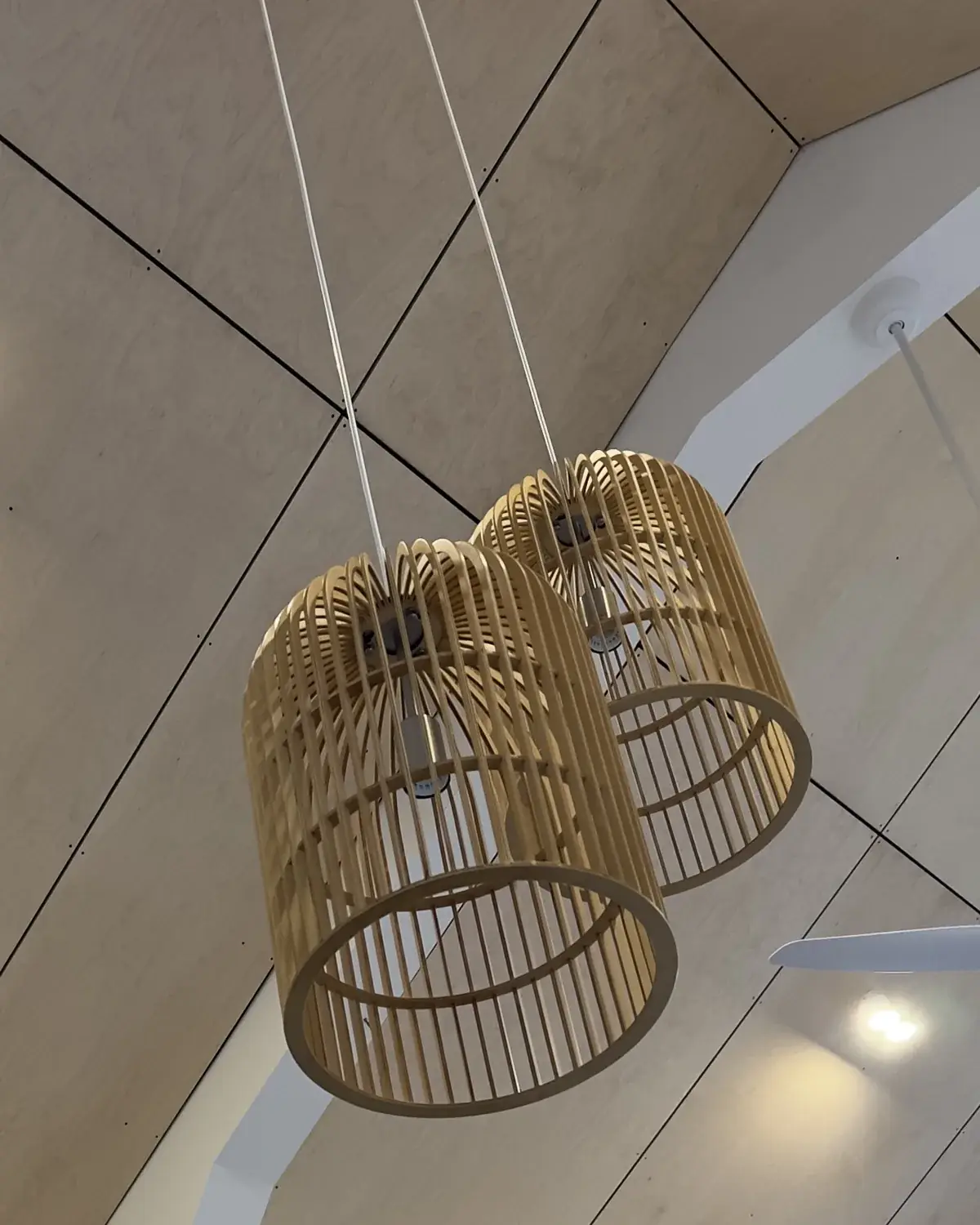 Timber pendant lights, wall sconces and ceiling fan on a raked timber ceiling